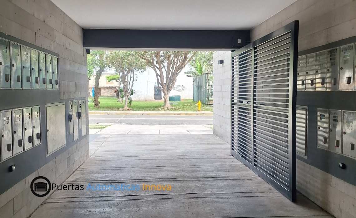 Puerta batiente automática de una hoja con motor de uso intensivo instalada en edificio por Puertas Automáticas Innova SAC